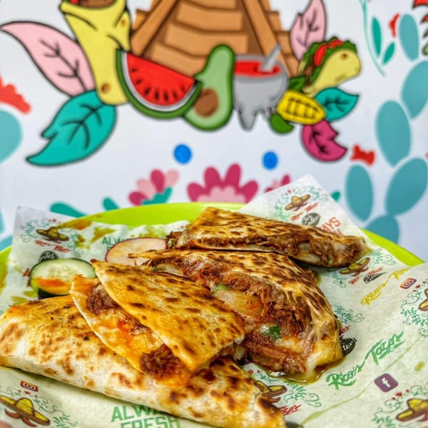 Rico's Tacos quesadillas with melted cheese and meat, served on branded paper with a colorful mural background.
