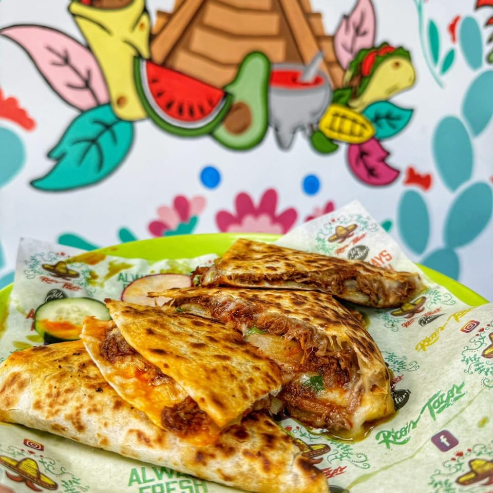 Rico's Tacos quesadillas with melted cheese and meat, served on branded paper with a colorful mural background.