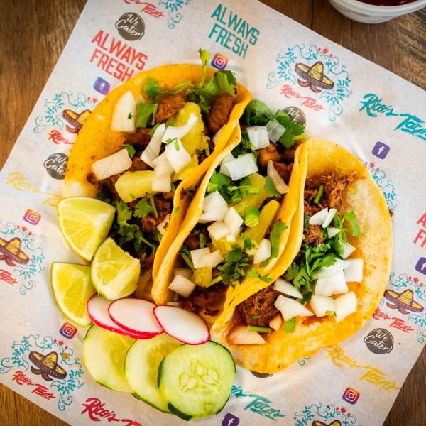 Three Rico's Tacos with meat, onions, cilantro, and pineapple, served with lime, radish, and cucumber.
